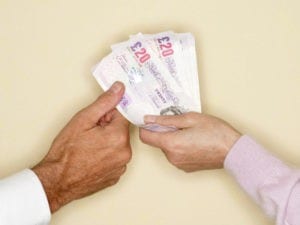 Woman giving twenty pound banknotes to man, close up hands